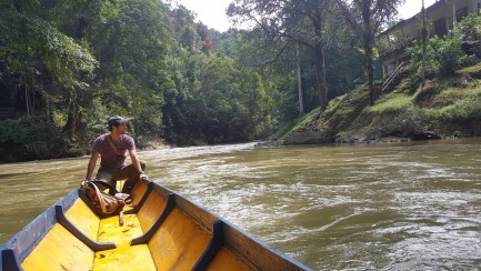 Man in stern of canoe as it goes down a river
