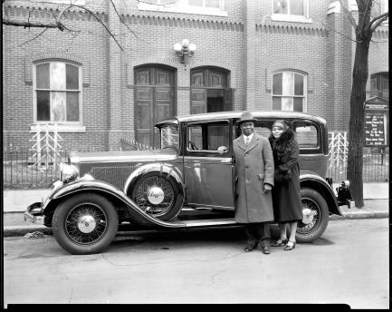 Couple stands next to old sedan