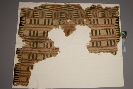 Image of a old blanket with only parts of the left and top border intact.