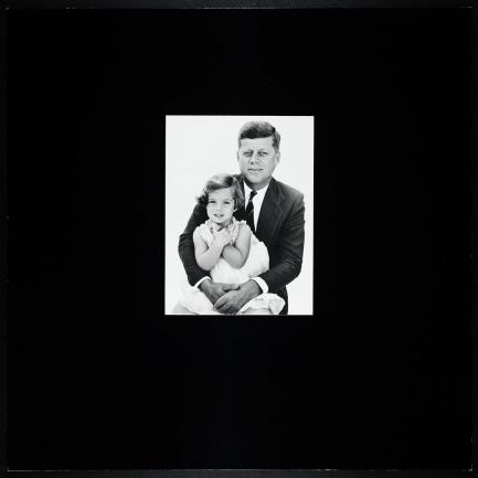 Black and white photo of JFK holding young Caroline