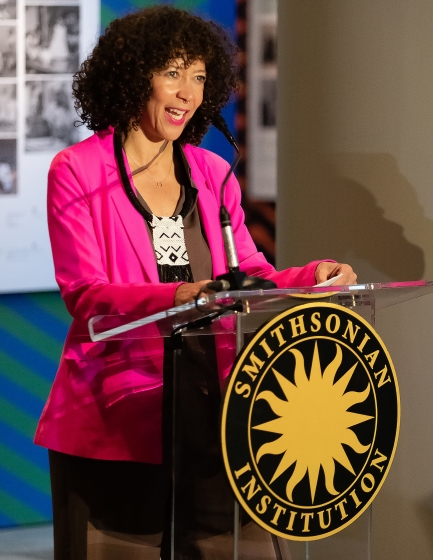Woman in pink blazer speaks at podium with Smithsonian Institution logo