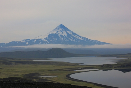 Volcano overlooking green landscape and small bodies of water on a hazy day