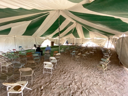 Empty chairs underneath a large outdoor tent