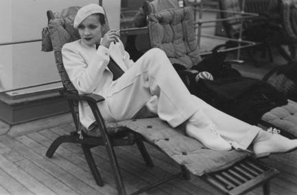 Marlene Dietrich dressed in white lounging on deck chair