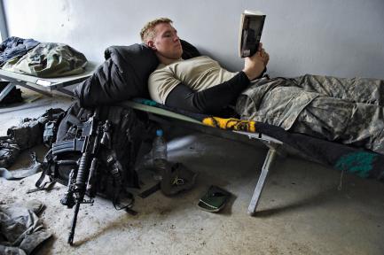 soldier reading while lying on cot