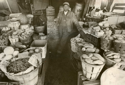 Man stands amid fruit and vegetable baskets