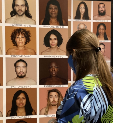 Woman wearing mask looks at wall of portrait photography