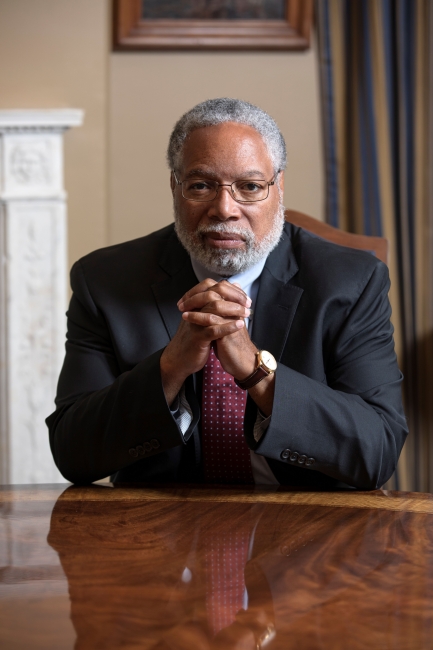 Lonnie Bunch sits at table with hands folded under chin