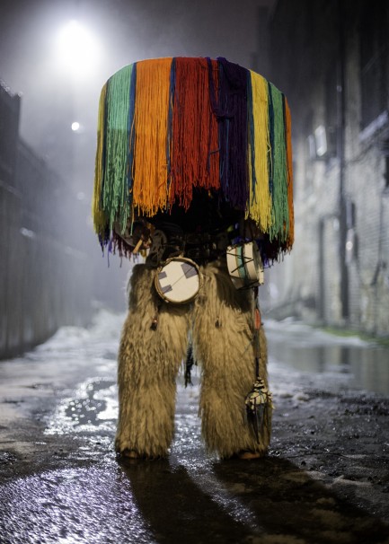 Person standing on city street completely obscured by colorful native costume