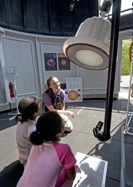 Children listen as woman explains telescope