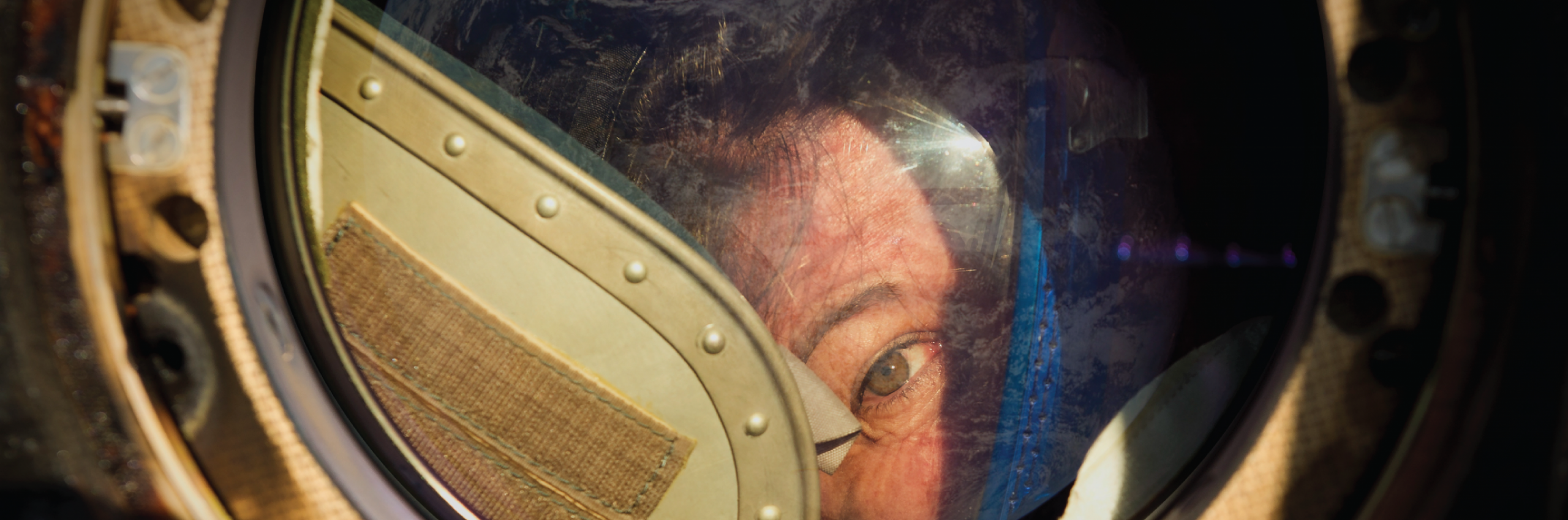 Partial view of mans face peering through a round window. 