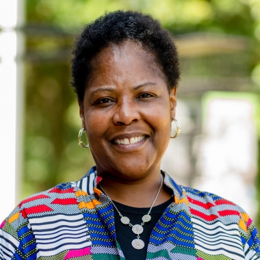 Woman stands outside, smiling