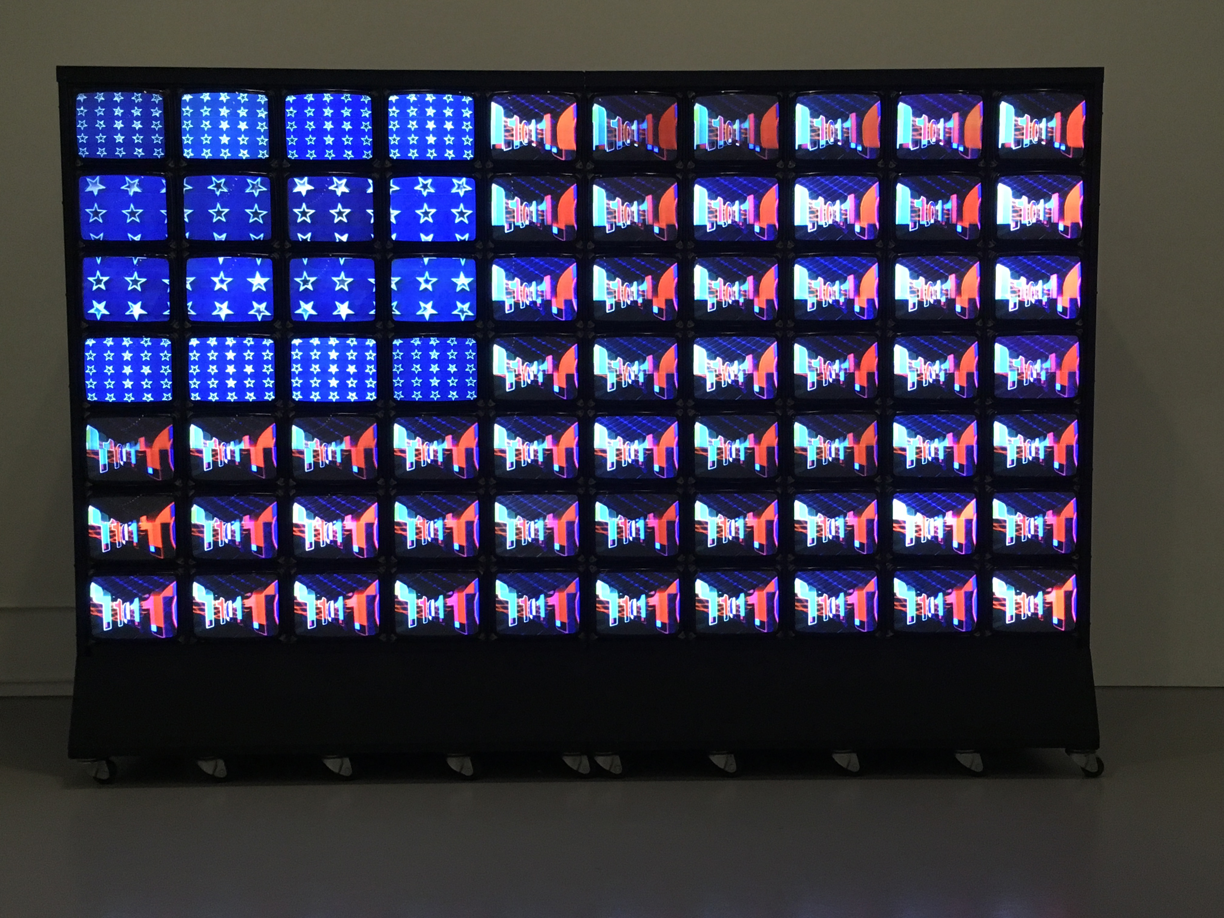 Wall of stacked video monitors displaying artwork